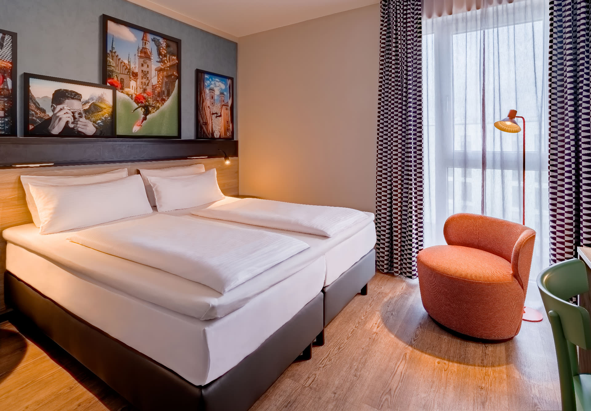 Doppelzimmer mit Fenster, Vorhang und Kunstwerken über dem Bett